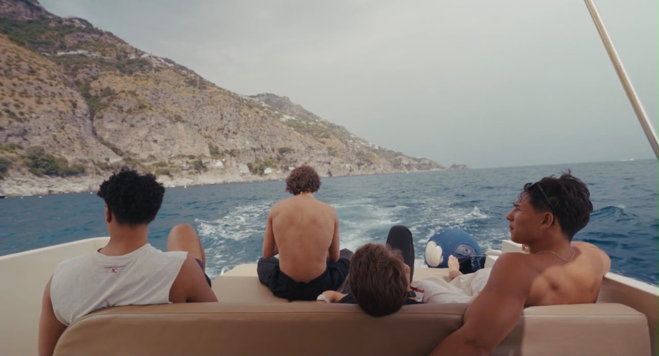 Marcel and three mates on the back of a boat, looking out at the Amalfi coastline.